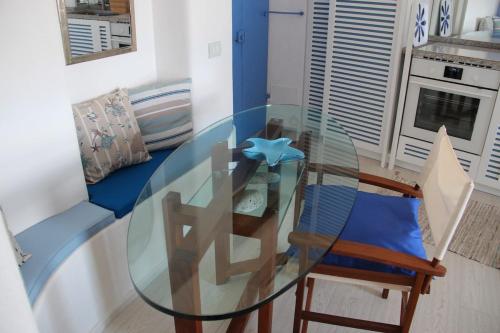 a glass table in a room with a chair and a couch at Occhio sul mare in Isola del Giglio