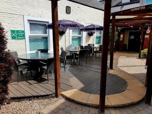 a patio with a table and chairs and umbrellas at Dancenter East Midlands Airport in Derby