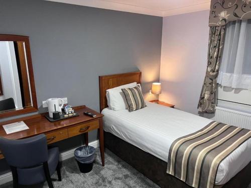 a hotel room with a bed and a desk with a computer at Dancenter East Midlands Airport in Derby