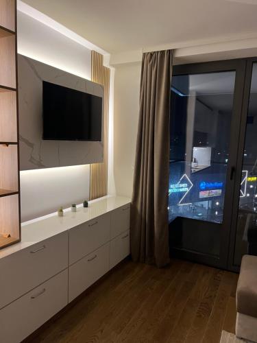 a living room with a tv and a large window at LiboroPlanet in Niš