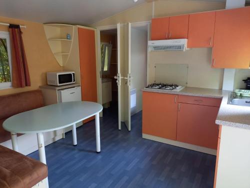 une petite cuisine avec des armoires orange et une table dans l'établissement Camping de Salviac, à Salviac