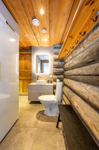 a bathroom with a toilet and a wooden wall at Aurinkorinne in Ruka