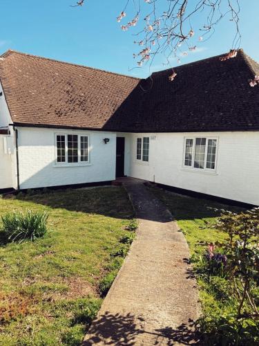 a white house with a black roof and a driveway at Elms Farm Cottages - White Swans in Icklesham