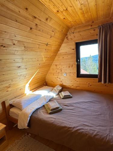 a bed in a wooden room with a window at Nest&Rest-Vikendice Tara 2 in Sekulić 