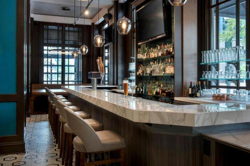 a bar with a long counter with chairs and glasses at Norfolk Waterside Marriott in Norfolk