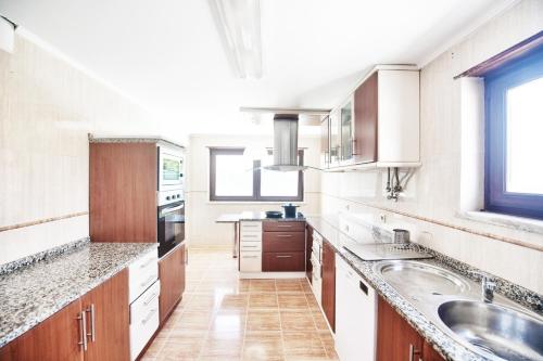 a kitchen with white cabinets and a sink at Aomo-casa parede in Parede
