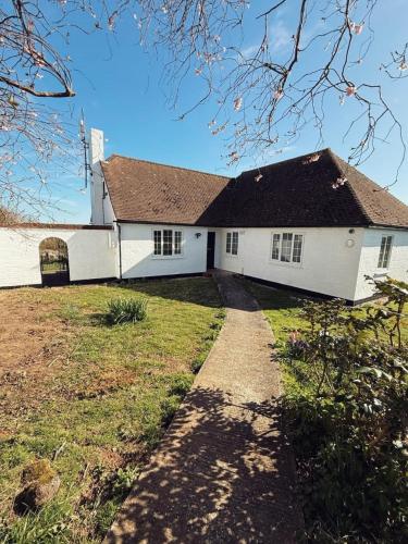 a white house with a black roof at Elms Farm Cottages - White Swans in Icklesham
