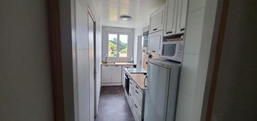 une cuisine avec des armoires blanches et un micro-ondes dans l'établissement Mes vacances à la mer, à Saint-Jean-de-Monts