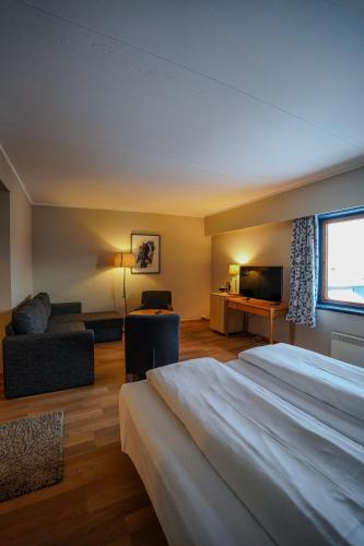 a hotel room with a large bed and a television at Reisafjord Hotel in Sørkjosen