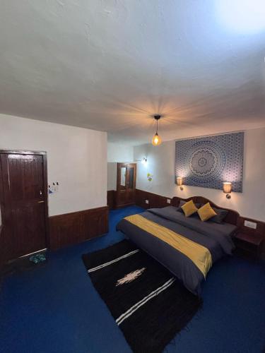 a bedroom with a large bed and blue carpet at Basecamp Manali in Manāli
