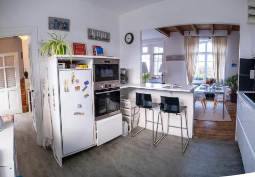 Il comprend une cuisine équipée d'un réfrigérateur et d'une table avec des chaises. dans l'établissement La maison aux volets bleus à 300m de la plage, à Locquirec