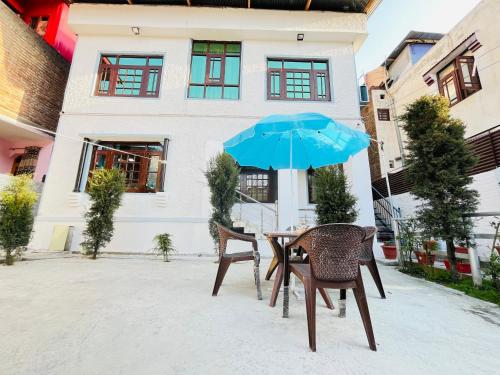 a table and two chairs with a blue umbrella at Sea Green Guest House in Srinagar