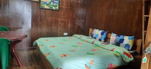a bed in a room with a wooden wall at Bluepine Cottages Pangot in Nainital