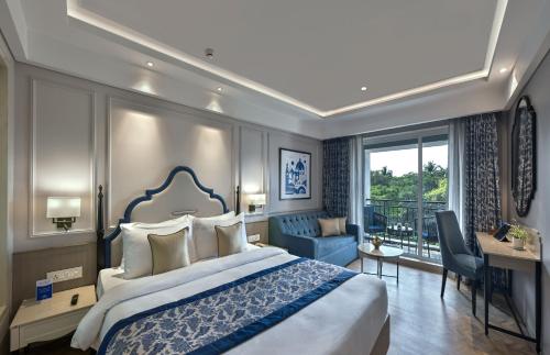 a bedroom with a large bed and a desk at Meritas Auberge Calangute Goa in Calangute