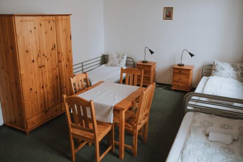 a room with two beds and a table and chairs at Pokoje Gościnne Domu Pielgrzyma w Supraślu in Supraśl