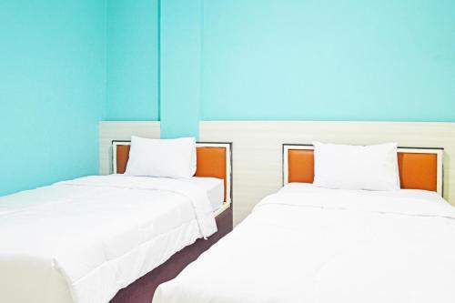 two white beds in a room with blue walls at Collection O Balikpapan Near Balikpapan Super Block Formerly City Inn Hotel in Balikpapan
