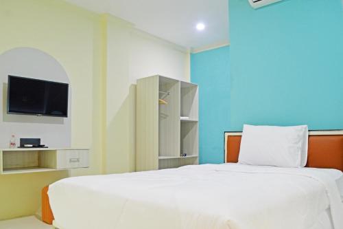 a bedroom with a white bed and a tv at Collection O Balikpapan Near Balikpapan Super Block Formerly City Inn Hotel in Balikpapan