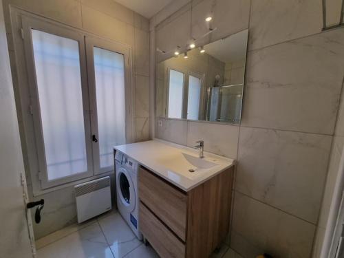 une salle de bain avec un lavabo et une machine à laver dans l'établissement Sea view flat 5 minutes from the beach, à Théoule-sur-Mer