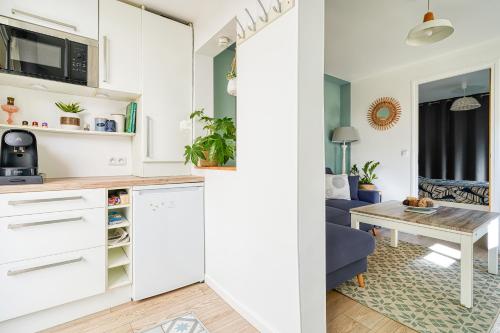 une cuisine avec des armoires blanches et une table dans une pièce dans l'établissement F2 Brunoy avec terrasse couverte, à Brunoy