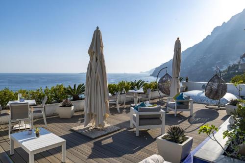 a patio with tables and chairs and an umbrella at Villa Pietra Santa in Positano
