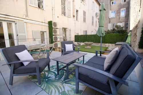 un patio avec des chaises, une table et un parasol dans l'établissement Chic 4 room apartment in the heart of Cannes amazing terrace!, à Cannes