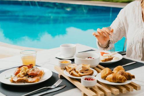 a table with plates of breakfast food next to a pool at Mr and Mrs White Corfu Couples Retreat Adults Only in Acharavi