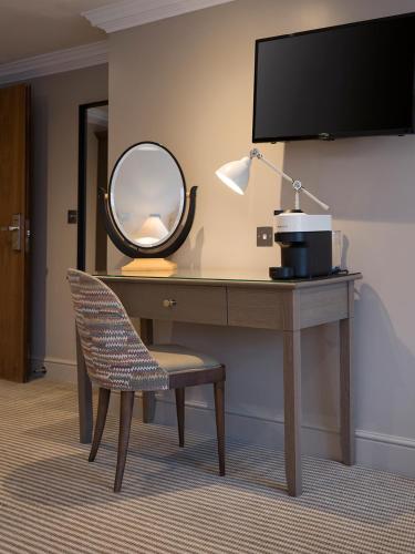 a desk with a mirror and a chair and a lamp at The Kings Arms in Christchurch