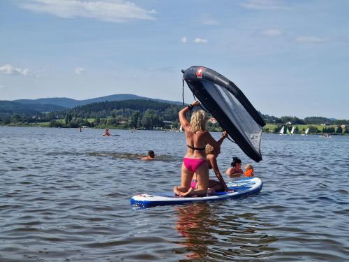 two people on a paddle board in the water at Relax Vila Lipno 1 u pláže Windy Point in Černá v Pošumaví