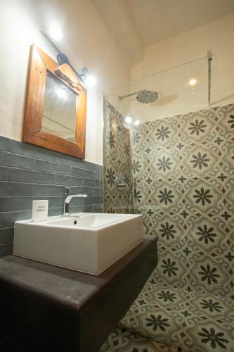 a bathroom with a sink and a mirror and tiles at Agriturismo Re Tarquinio in Tuscania