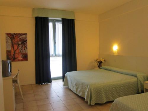 a hotel room with two beds and a window at Lieta Sosta in Colfiorito
