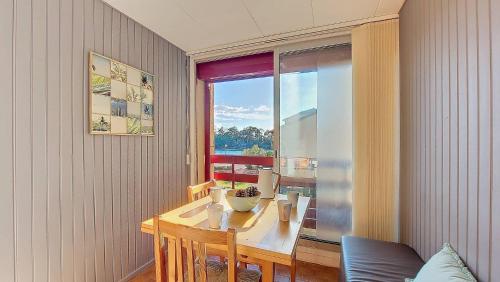 une salle à manger avec une table et une grande fenêtre dans l'établissement S-Lac 04-Soustons Appartement 4 personnes dans résidence au bord du lac marin, à Soustons
