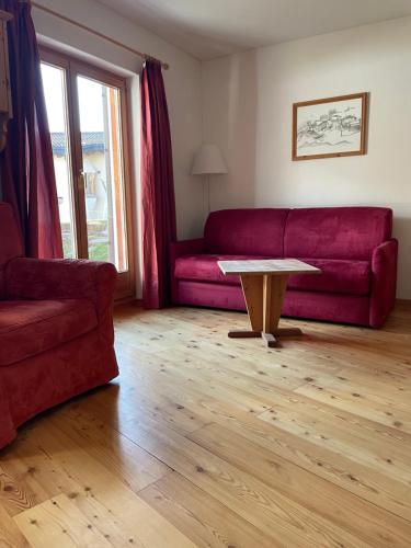 a living room with a red couch and a table at Residence Miragolf in Madulain