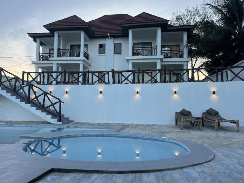 a villa with a swimming pool in front of a house at Alfa Boutique Hotel in Kiwengwa
