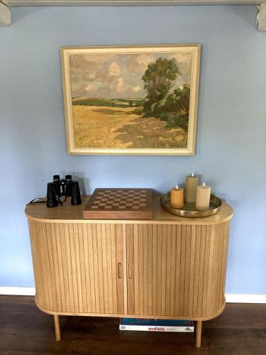 a wooden cabinet with a painting on the wall at Cozy holiday home in Dalby