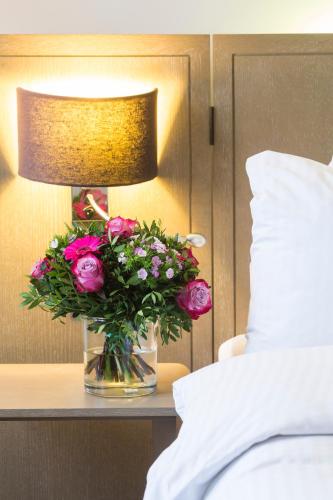 a vase of flowers on a table next to a lamp at Park Inn by Radisson Antwerp City Centre in Antwerp