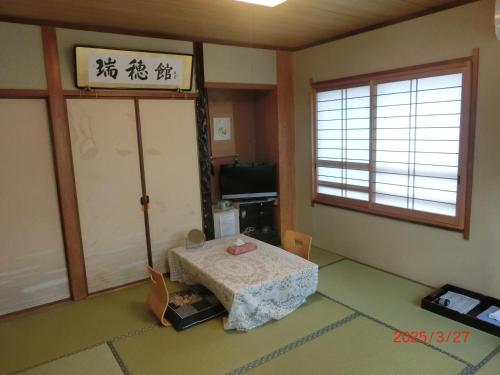 a room with a table and a window and a door at Mizuhokan in Ise