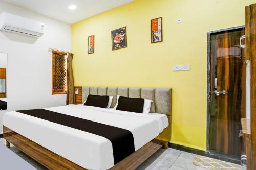 a bedroom with a large white bed and yellow walls at Hotel O katyayani in Indore
