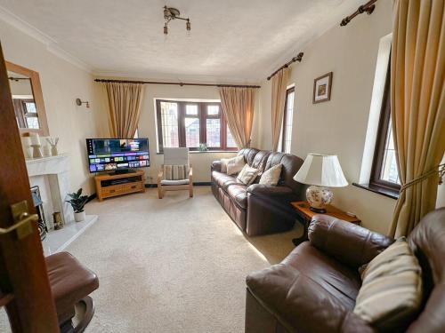 a living room with leather couches and a television at Maesllan - A Spacious Holiday Home in Porthcawl - 5 bedrooms, sleeps up to 10 people in Porthcawl
