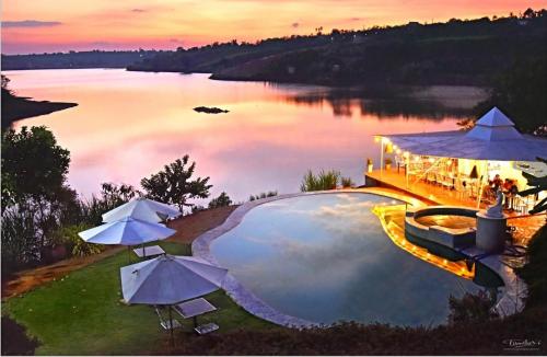 a pool with umbrellas next to a body of water at Du Lịch Lâm Hà - Hồ Gia Trang Villas in Lam Ha