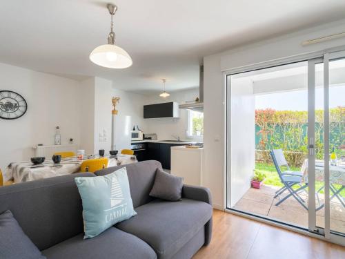 Il comprend un salon avec un canapé gris et une cuisine. dans l'établissement Carnac : Appartement T2 de standing, 49m², proche marché, plage et Thalasso, Parking Inclus - FR-1-477-243, à Carnac