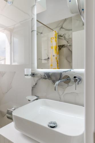 a white bathroom with a sink and a mirror at Huna Apartment in Sarandë