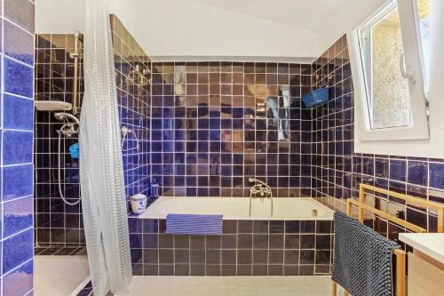 La salle de bains est pourvue de carrelage bleu, d'une baignoire et d'un lavabo. dans l'établissement Villa 4 chambres - piscine - parking - clim, à Saint-Raphaël