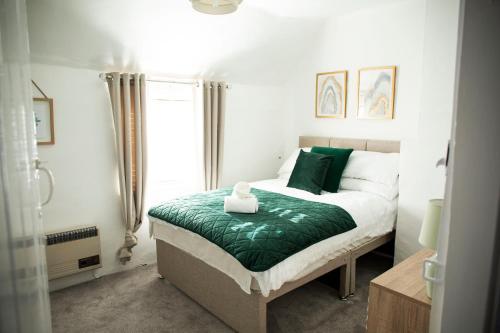 a bedroom with a bed with green sheets and a window at Laburnum Cottages - Stratford upon Avon in Stratford-upon-Avon