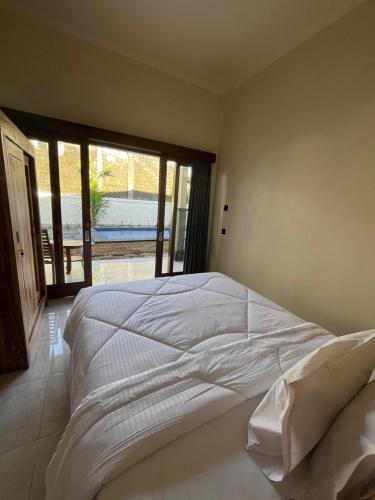 a large white bed in a bedroom with a window at Brian Homestay in Nusa Dua