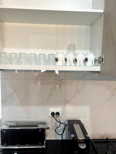 a kitchen with a shelf with cups on it at Amukta nook in Truganina