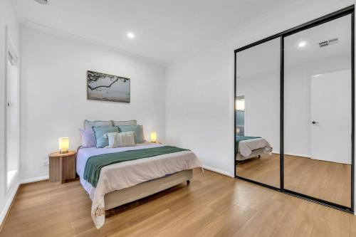 a white bedroom with a bed and a mirror at Amukta nook in Truganina