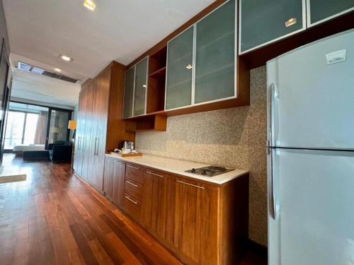 a kitchen with wooden cabinets and a white refrigerator at Wish Inn Silom BKK - วิช อินน์ สีลม in Bang Rak
