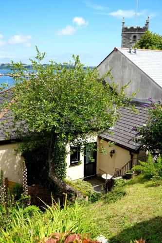 a small white house with a tree in the yard at Fabulous High Street Townhouse With Stunning Views & Parking at 'Eagles Nest' in Falmouth