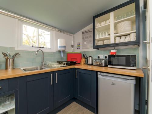 a kitchen with blue cabinets and a sink and a microwave at YHA Street in Street