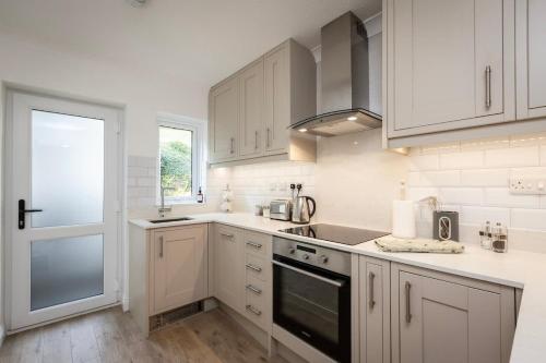 a white kitchen with white cabinets and a window at Fabulous High Street Townhouse With Stunning Views & Parking at 'Eagles Nest' in Falmouth